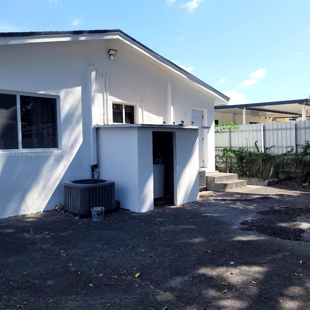 view of side of home with stucco siding, fence, and central air condition unit