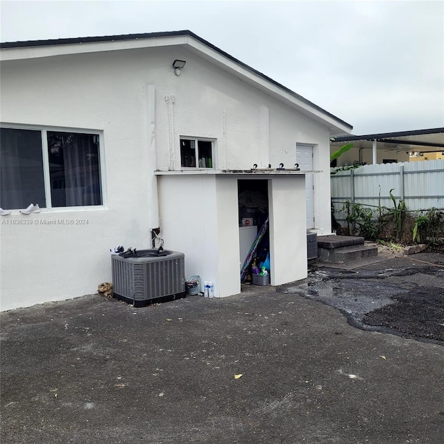 rear view of property with fence, central AC unit, and stucco siding