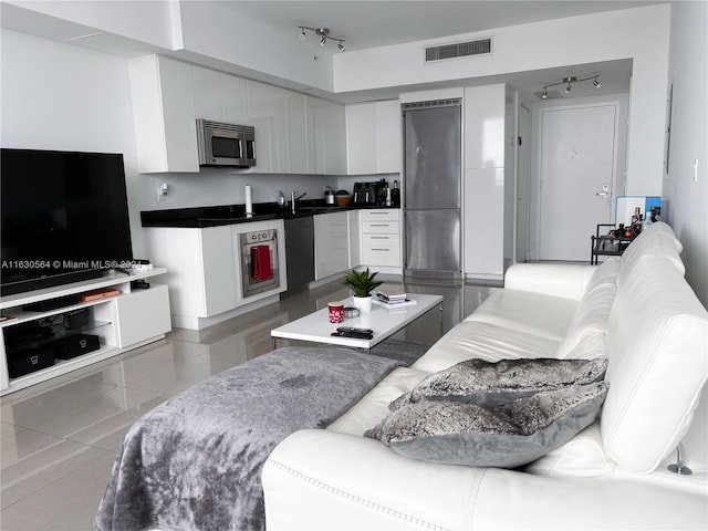 tiled living room with sink, rail lighting, and beverage cooler