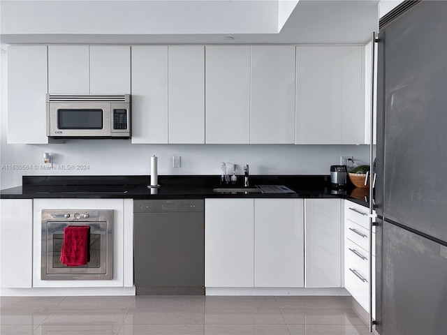 kitchen featuring white cabinets, dark countertops, stainless steel appliances, and a sink