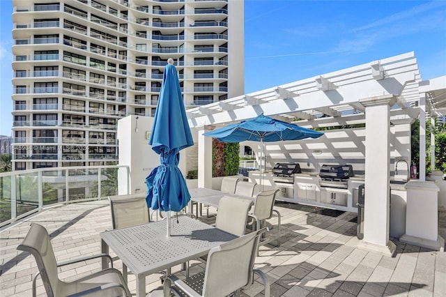 view of patio with a pergola, area for grilling, a balcony, and exterior kitchen