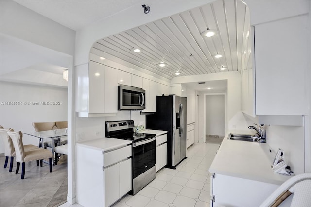 kitchen with appliances with stainless steel finishes, white cabinets, light tile patterned floors, and sink