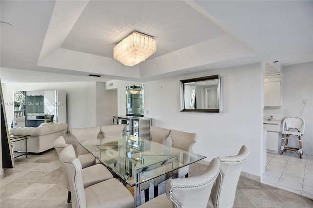 dining area with light tile patterned floors, a raised ceiling, and a notable chandelier