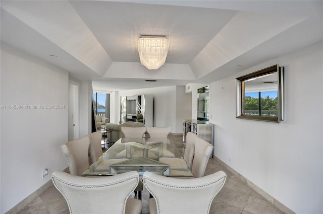 tiled living room featuring a raised ceiling and an inviting chandelier