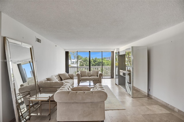 tiled living room with a textured ceiling and floor to ceiling windows