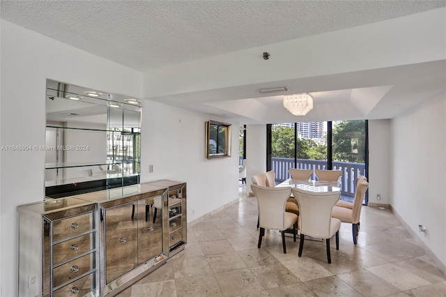 dining room with light tile patterned flooring, a chandelier, a textured ceiling, and a tray ceiling