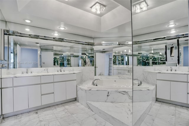 bathroom featuring tiled tub, a raised ceiling, vanity, and tile patterned floors