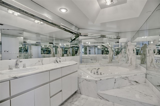 bathroom featuring a tray ceiling, a relaxing tiled tub, tile patterned flooring, and vanity