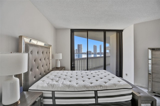 carpeted bedroom with expansive windows, a textured ceiling, and access to exterior