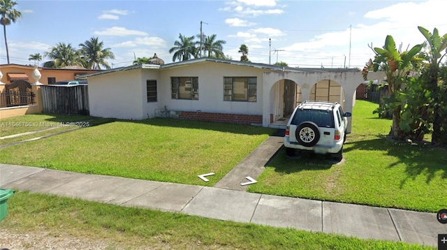 view of front of property with stucco siding, fence, and a front yard