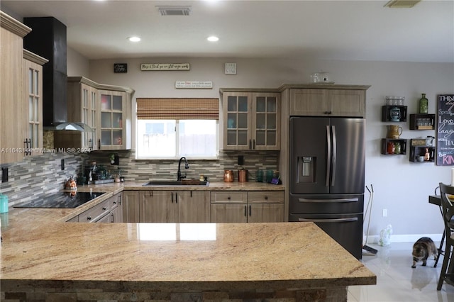 kitchen featuring stainless steel fridge, decorative backsplash, wall chimney exhaust hood, black electric stovetop, and sink