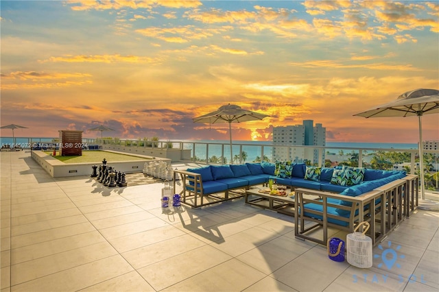 patio terrace at dusk featuring a water view and an outdoor living space