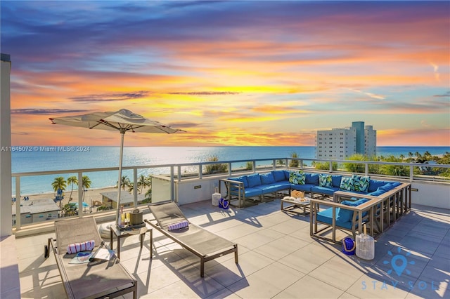 patio terrace at dusk featuring a balcony, an outdoor living space, and a water view