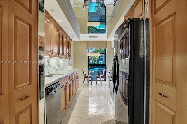 kitchen featuring decorative backsplash, stainless steel dishwasher, sink, and black refrigerator