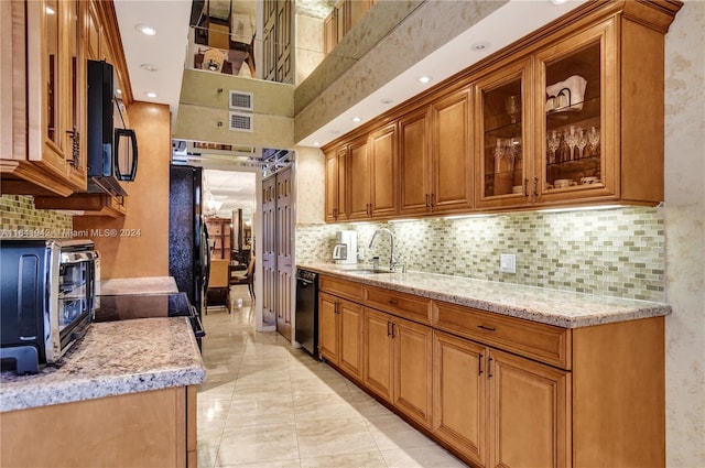 kitchen featuring decorative backsplash, light stone counters, light tile patterned floors, black appliances, and sink