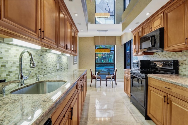 kitchen with light stone countertops, black appliances, tasteful backsplash, and sink