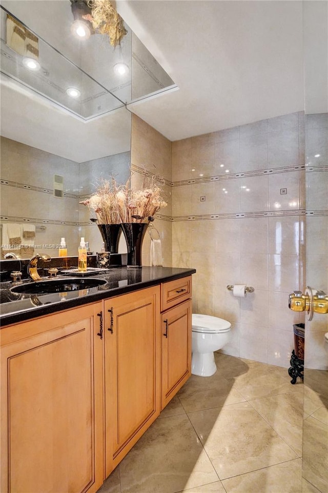 bathroom featuring vanity, tile walls, tile patterned flooring, and toilet