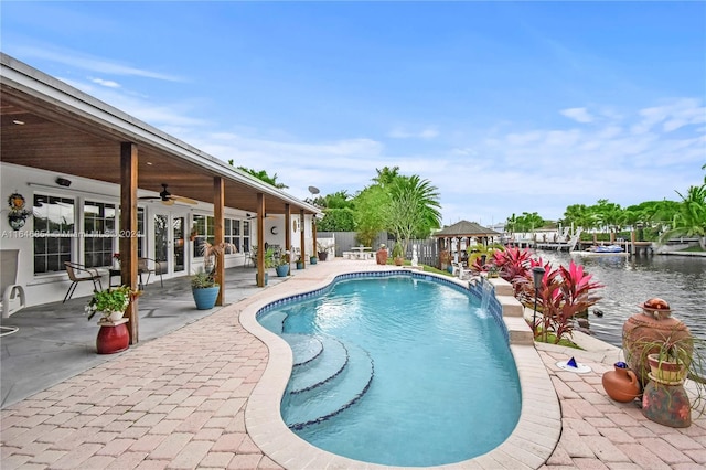 view of swimming pool with pool water feature, ceiling fan, a water view, and a patio