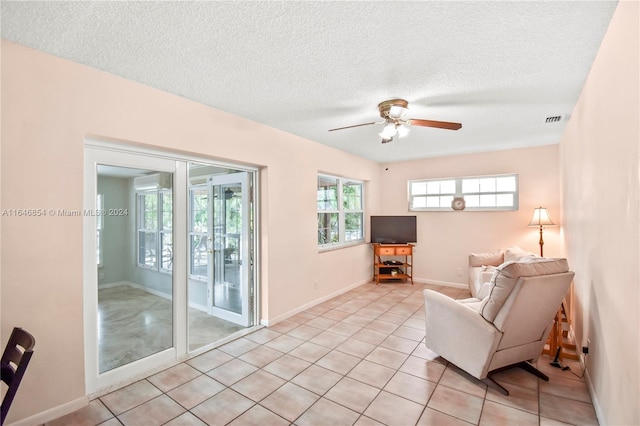 sitting room featuring a textured ceiling, ceiling fan, and light tile patterned flooring