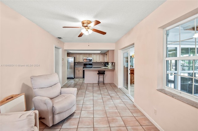 living room with ceiling fan, light tile patterned floors, and a textured ceiling