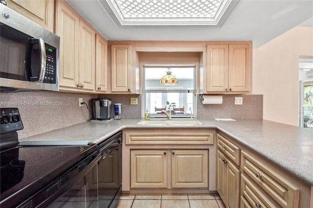 kitchen with plenty of natural light, light tile patterned floors, black appliances, and sink