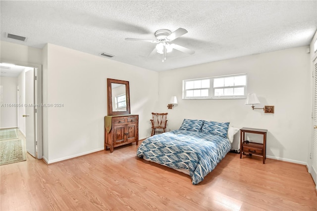 bedroom featuring ceiling fan, hardwood / wood-style floors, and a textured ceiling