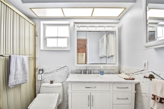 bathroom with vanity, tile walls, and toilet