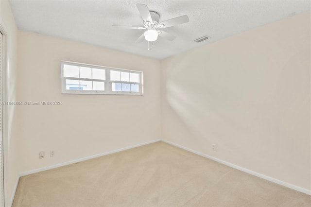 unfurnished room featuring a textured ceiling, light colored carpet, and ceiling fan