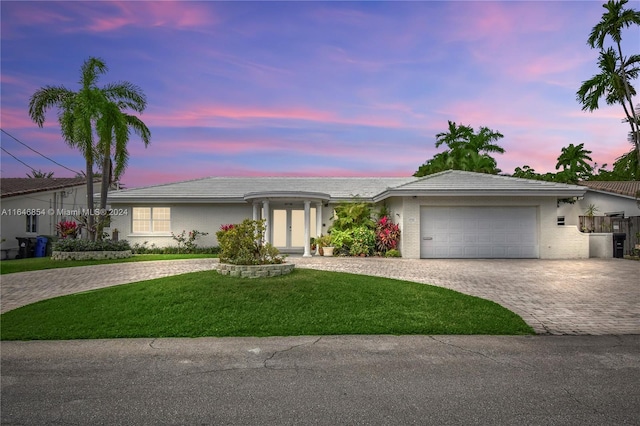 ranch-style house featuring a garage and a lawn