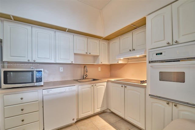 kitchen with light tile patterned floors, white appliances, sink, and white cabinets