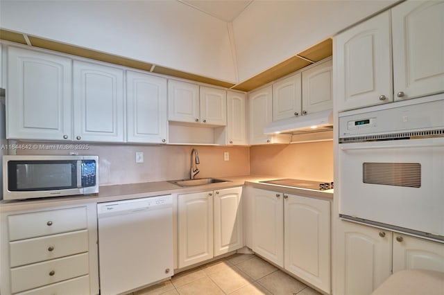 kitchen featuring under cabinet range hood, white appliances, a sink, white cabinetry, and light countertops