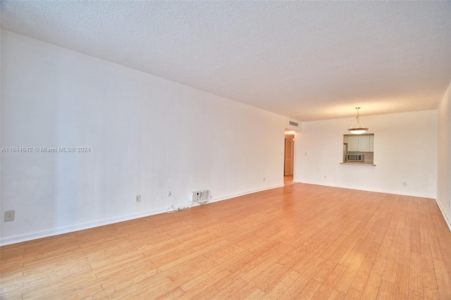 unfurnished room featuring light wood-type flooring and a textured ceiling