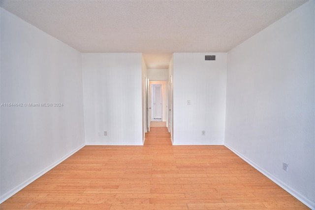 empty room with light hardwood / wood-style floors and a textured ceiling