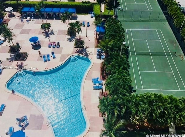 view of swimming pool featuring tennis court and a patio