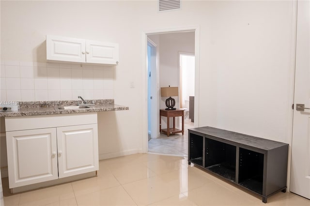 kitchen with decorative backsplash, white cabinetry, sink, and light tile patterned floors