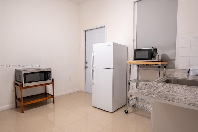 kitchen featuring white fridge, light tile patterned floors, and sink