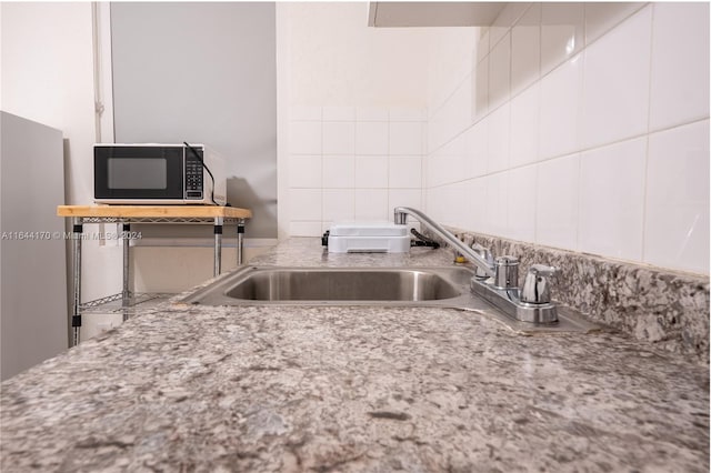 kitchen featuring decorative backsplash, light stone counters, white cabinetry, and sink