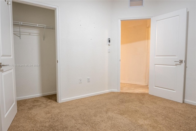 unfurnished bedroom with light colored carpet and a closet