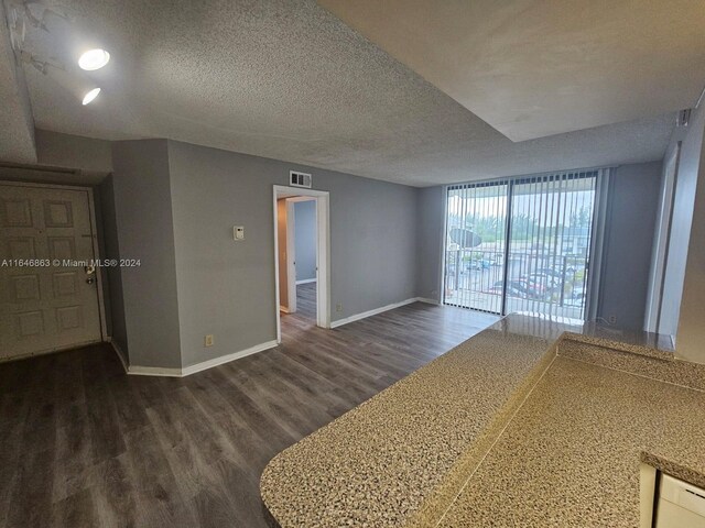 empty room with wood-type flooring, a textured ceiling, and expansive windows