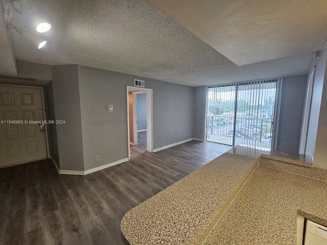 spare room featuring dark wood-style floors, a textured ceiling, visible vents, and baseboards