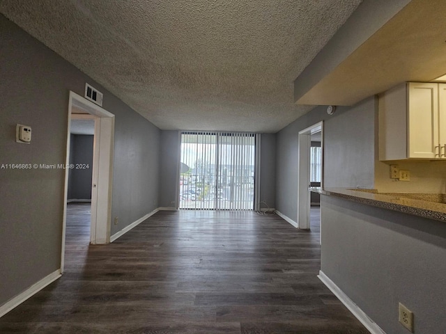 unfurnished living room featuring dark wood-type flooring, a textured ceiling, and floor to ceiling windows