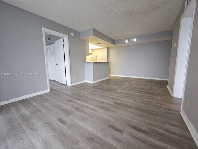 unfurnished living room with hardwood / wood-style flooring and a textured ceiling