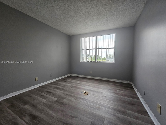 unfurnished room featuring dark wood-style floors, a textured ceiling, and baseboards