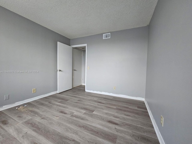 empty room with hardwood / wood-style flooring and a textured ceiling