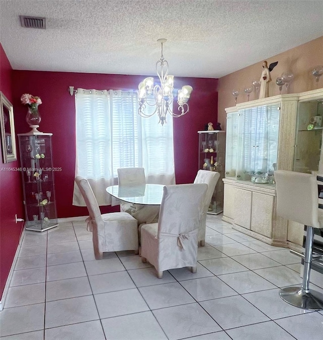 dining space featuring a notable chandelier, light tile patterned flooring, and a textured ceiling