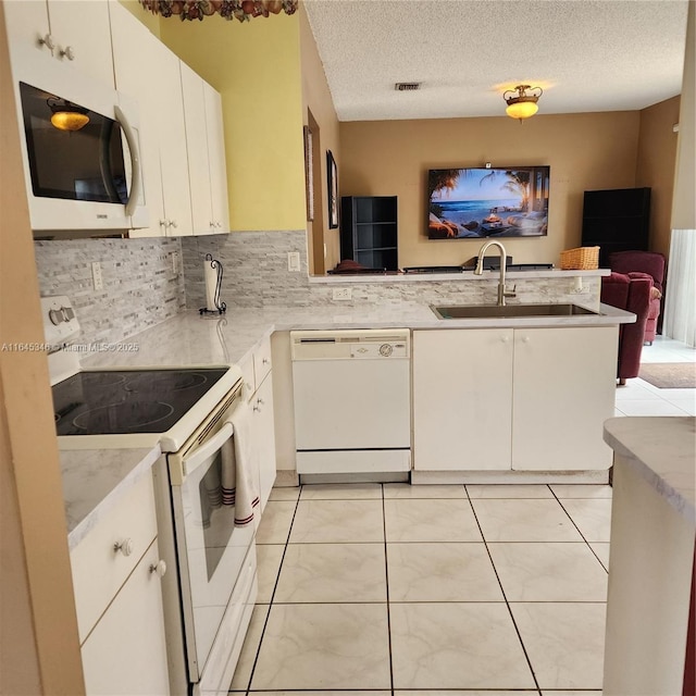 kitchen featuring sink, kitchen peninsula, a textured ceiling, white appliances, and white cabinets