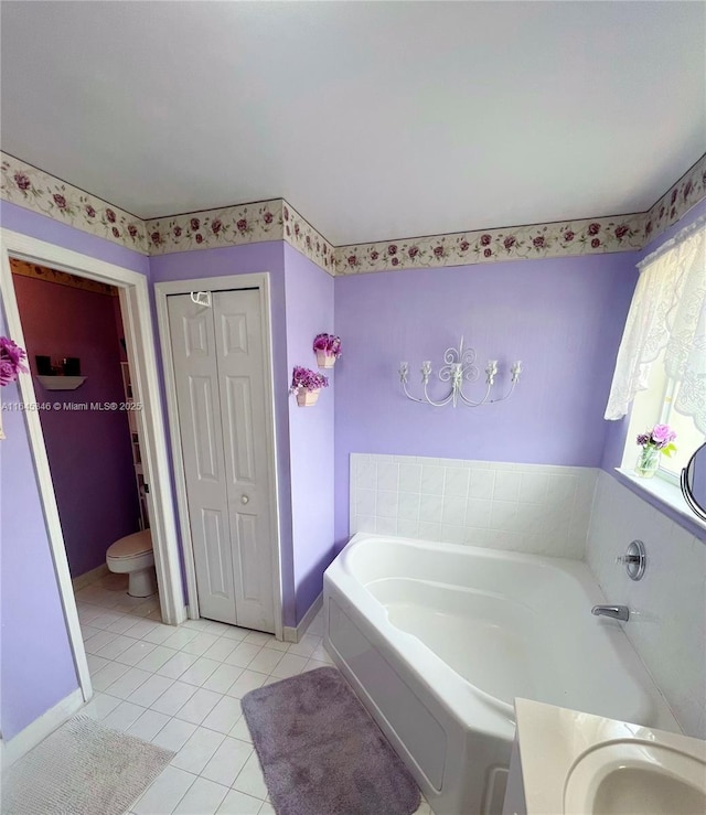 bathroom with tile patterned floors, a washtub, and toilet