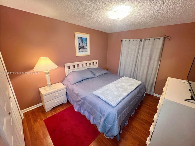 bedroom with a textured ceiling and dark wood-type flooring