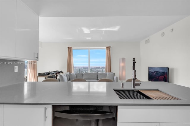 kitchen featuring visible vents, dishwasher, open floor plan, and white cabinetry