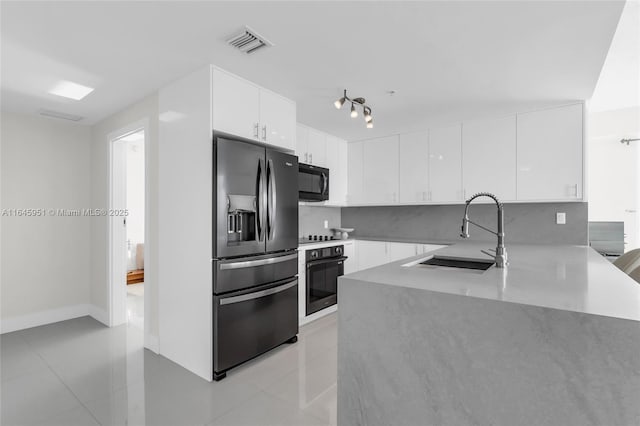 kitchen featuring visible vents, white cabinets, a sink, black appliances, and decorative backsplash
